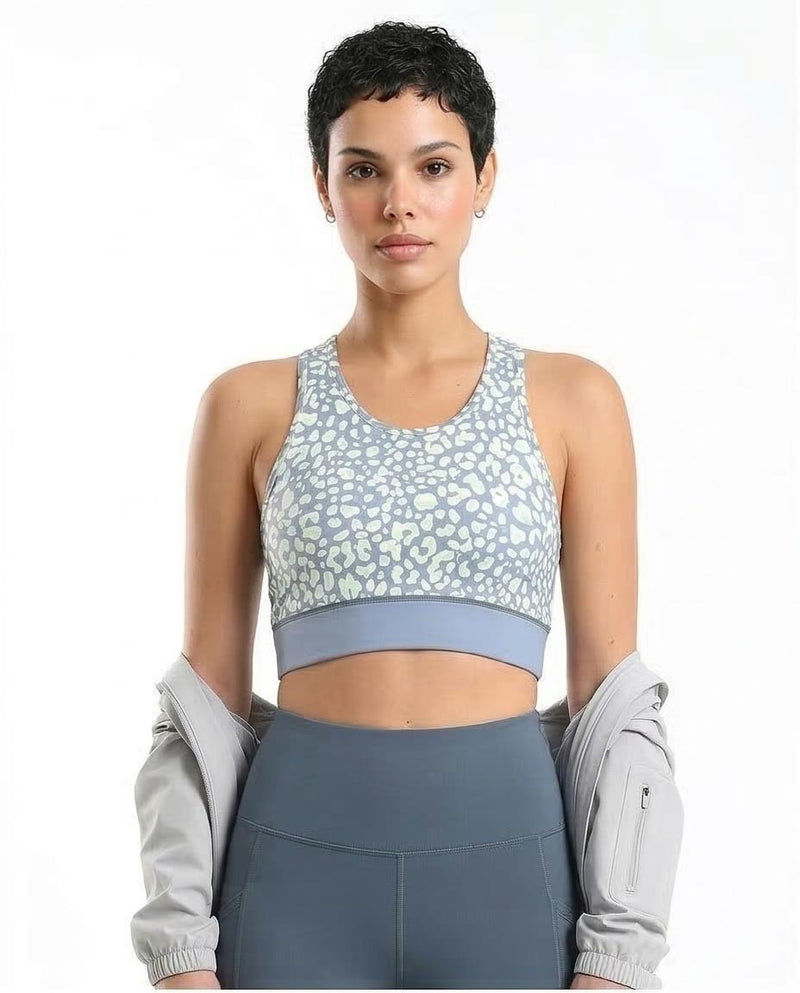 Woman wearing a patterned sports bra and leggings on a white background