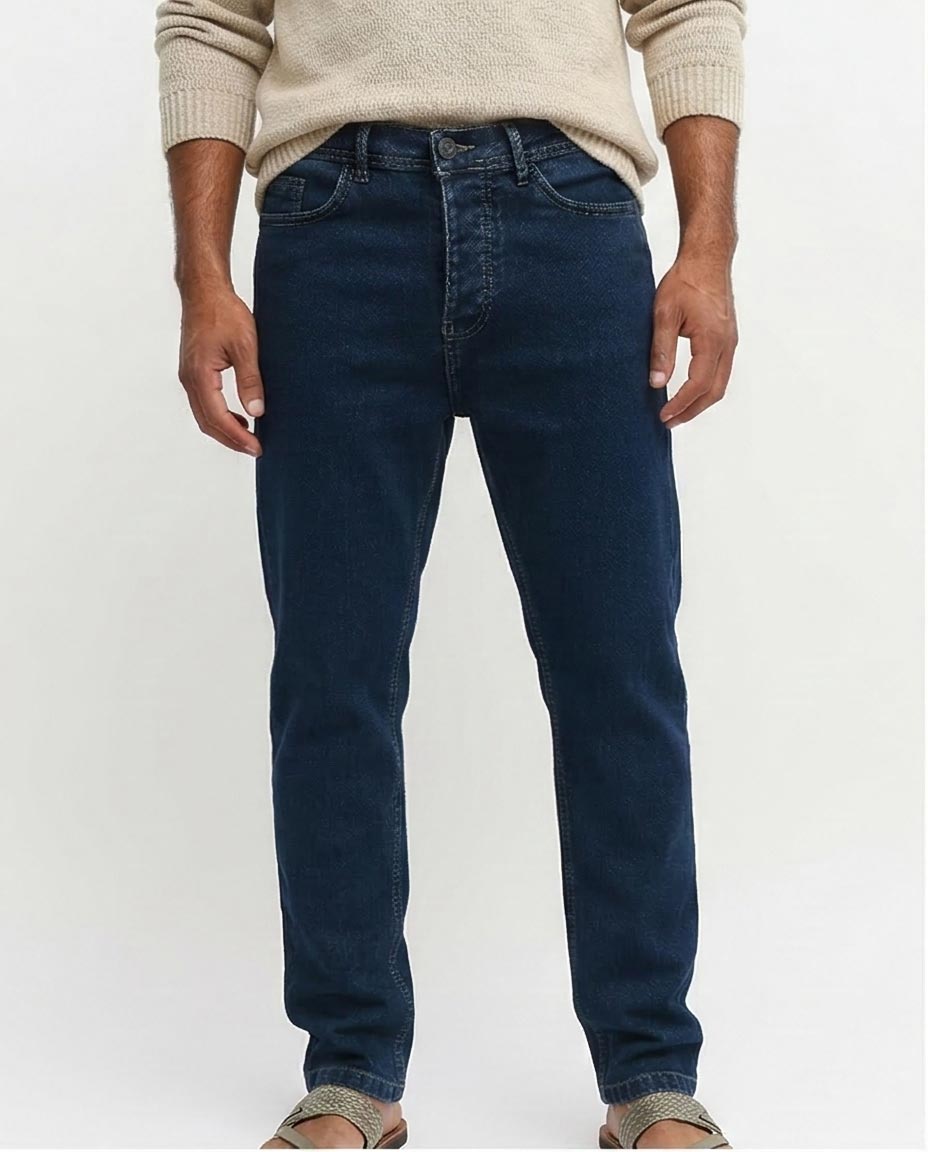 Person wearing blue jeans and a beige sweater on a white background