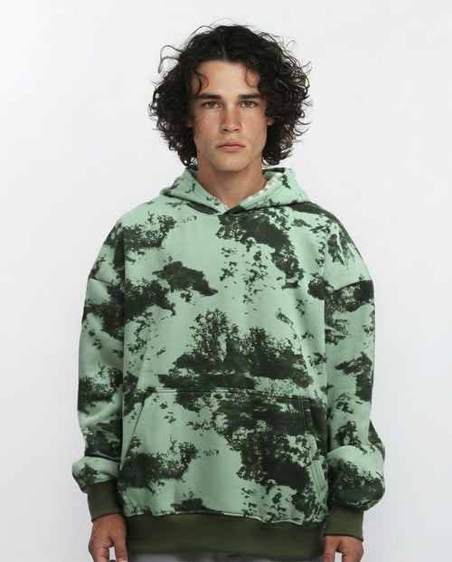 Person wearing a green camouflage hoodie on a white background