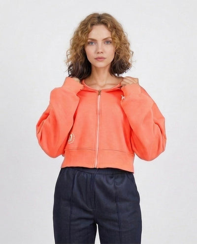 Woman wearing a bright orange hoodie with a plain background