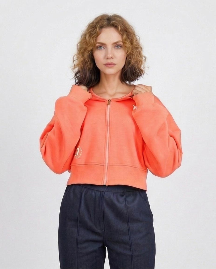 Woman wearing a bright orange hoodie with a plain background