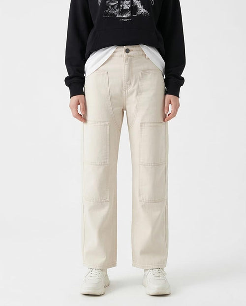 Woman wearing beige pants and a black sweatshirt with a graphic design on a white background