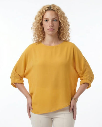 Woman wearing a mustard yellow blouse against a white background