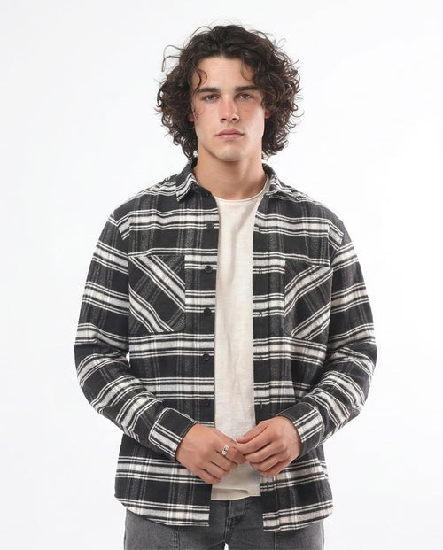 Person wearing a black and white plaid shirt over a white t-shirt on a white background