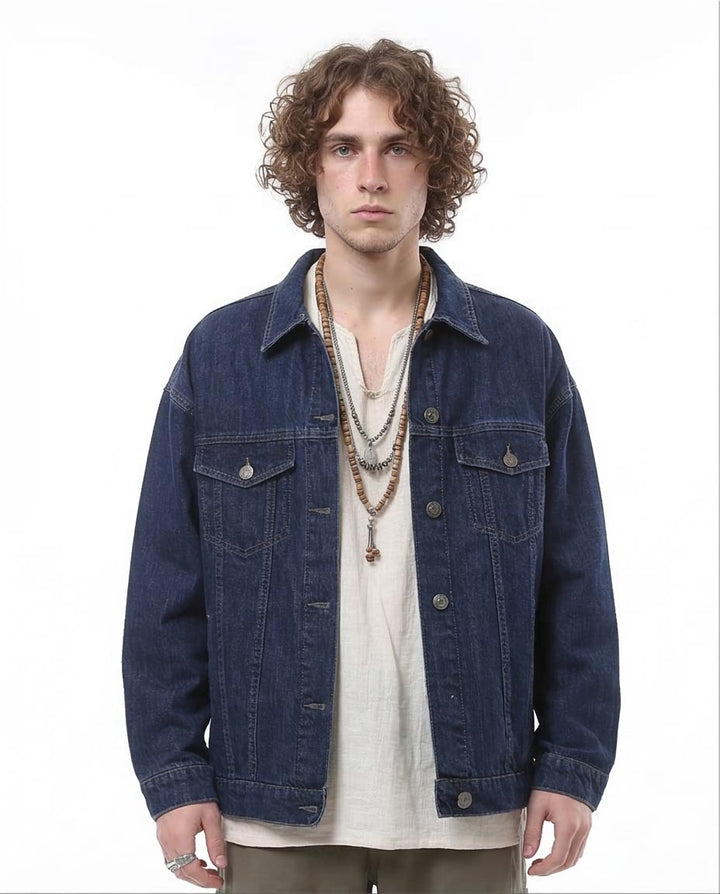 Man wearing a blue denim jacket over a white shirt on a white background