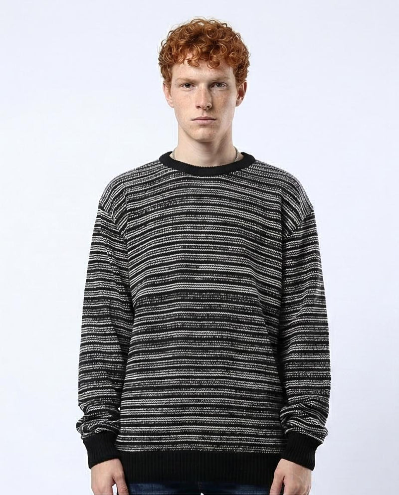 Man wearing a black and white patterned sweater on a white background