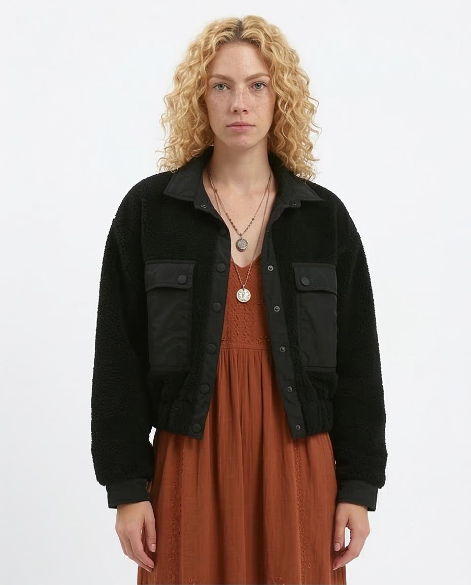 Woman wearing a black jacket over a brown dress on a white background