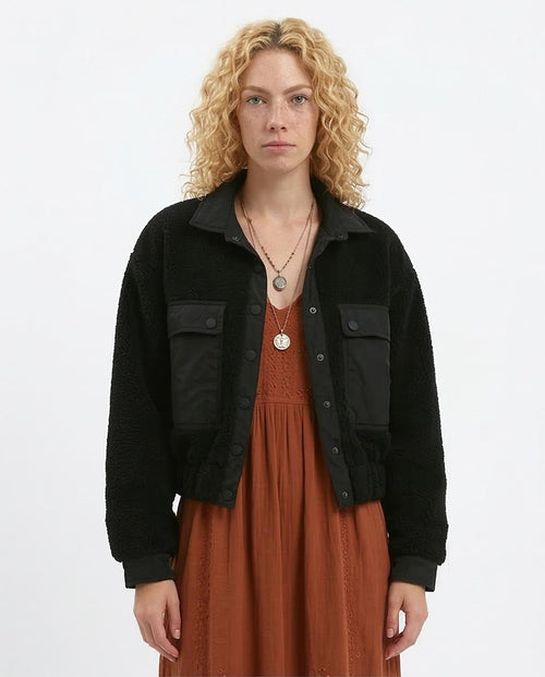 Woman wearing a black jacket over a brown dress on a white background