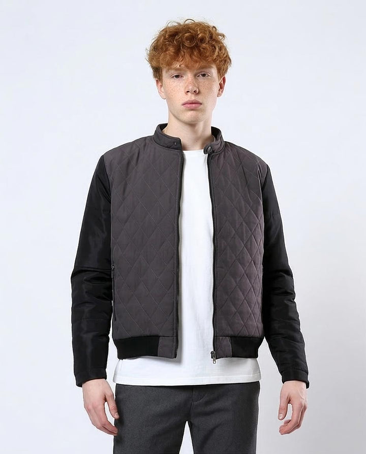 Person wearing a dark quilted jacket over a white shirt on a light gray background
