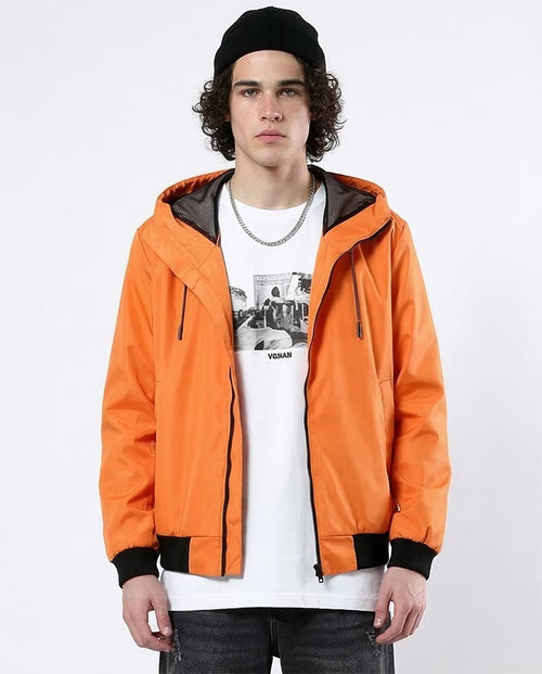 Person wearing an orange jacket with a black hood on a white background