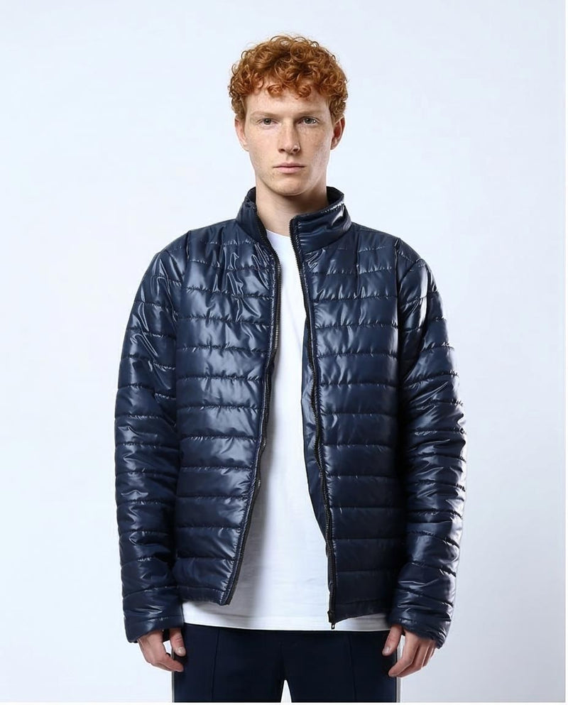 Man wearing a navy blue puffer jacket on a light gray background