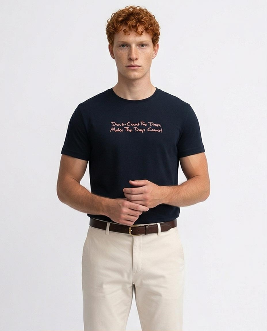Man wearing a navy t-shirt with text and beige pants on a white background