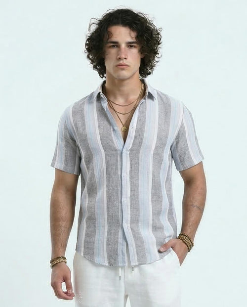 Man wearing a striped shirt and white pants against a light background