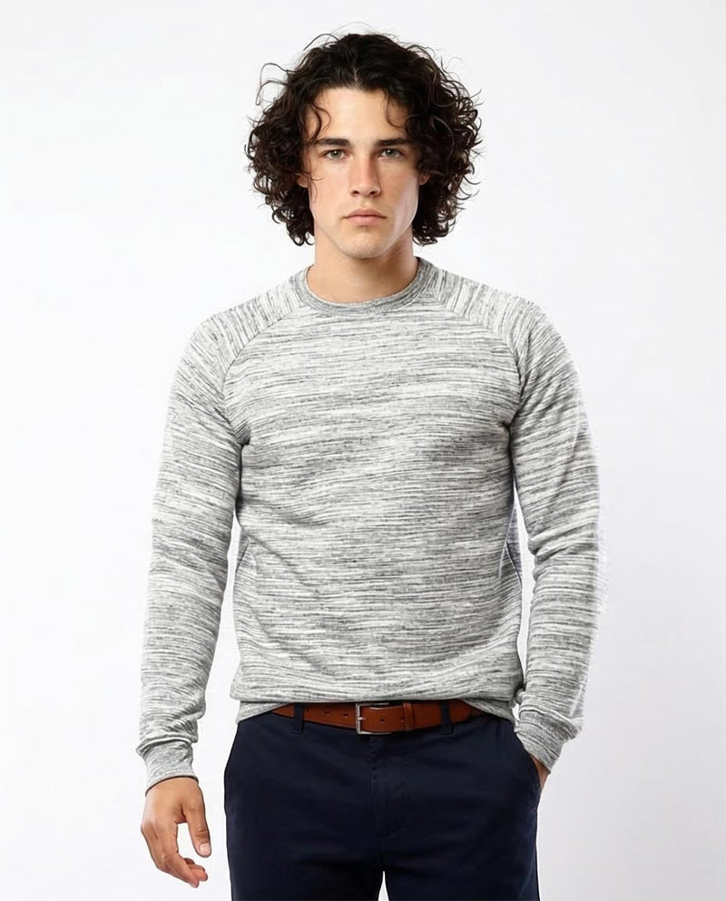 Man wearing a gray sweater and dark pants against a white background