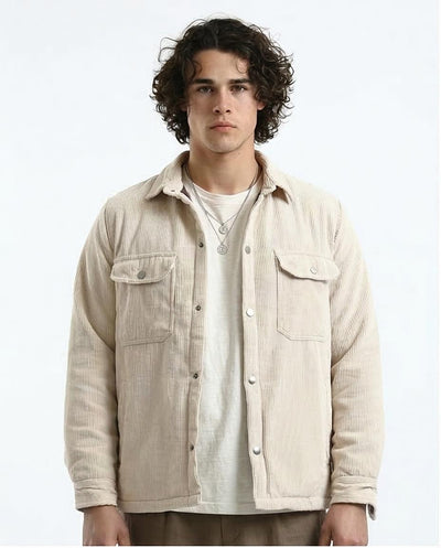 Man wearing a beige corduroy jacket over a white shirt on a white background