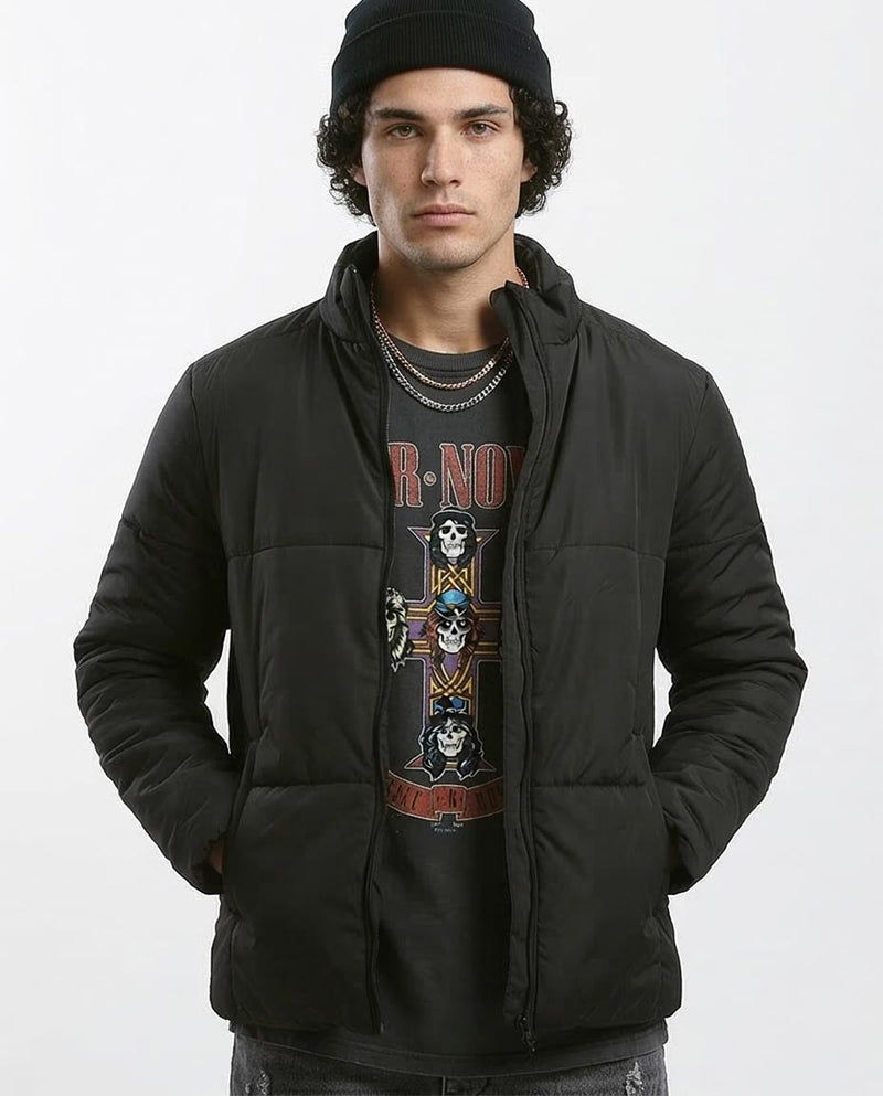 Man wearing a black jacket over a graphic t-shirt on a white background
