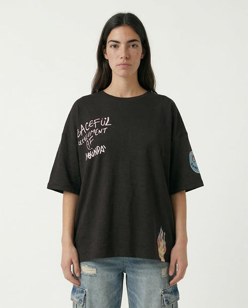 Person wearing a black t-shirt with text and patches on a white background