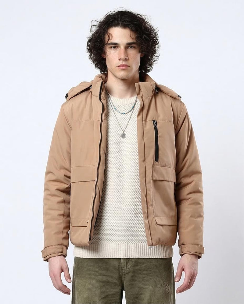 Man wearing a tan jacket over a white sweater on a white background