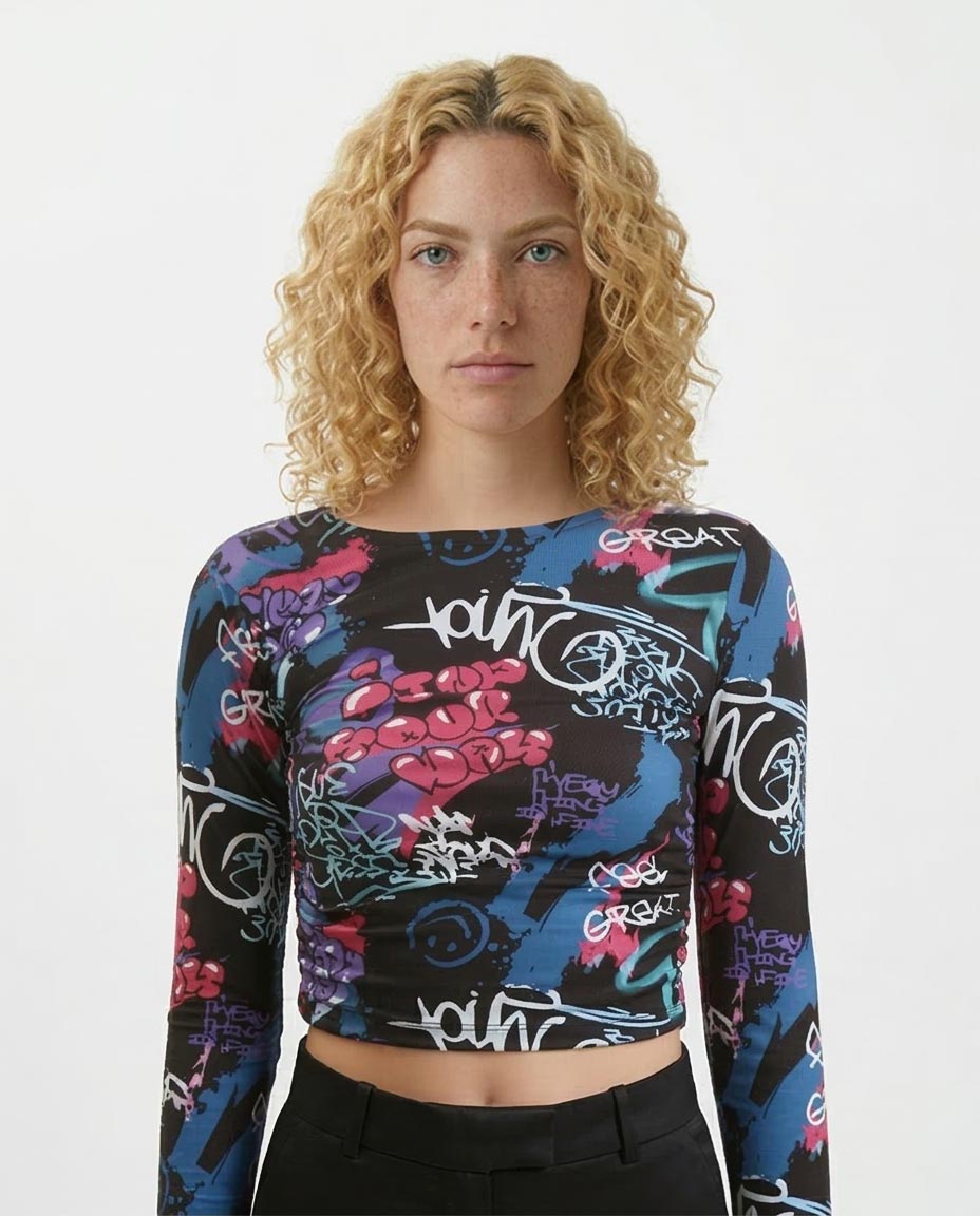 Person wearing a colorful long-sleeve crop top with graphic designs on a white background