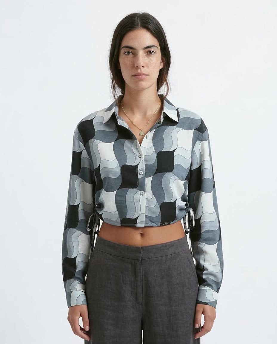 Person wearing a patterned shirt and gray pants on a white background