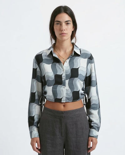 Person wearing a patterned shirt and gray pants on a white background