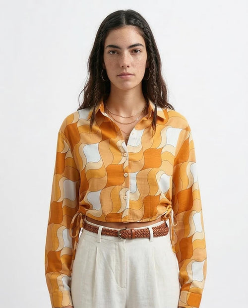 Woman wearing a patterned orange and white shirt with a plain background