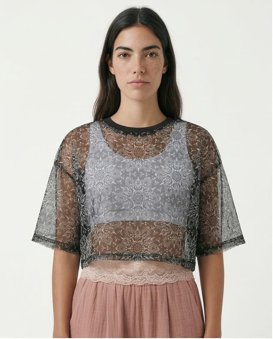 Woman wearing a sheer lace top with a plain background