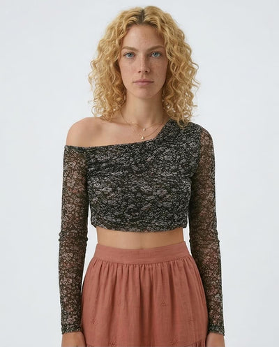 Woman wearing a black lace off-shoulder top and pink skirt on a white background