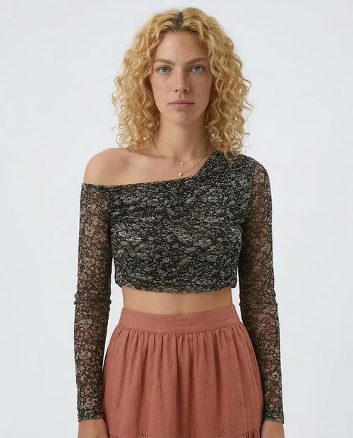 Woman wearing a black lace off-shoulder top and pink skirt on a white background