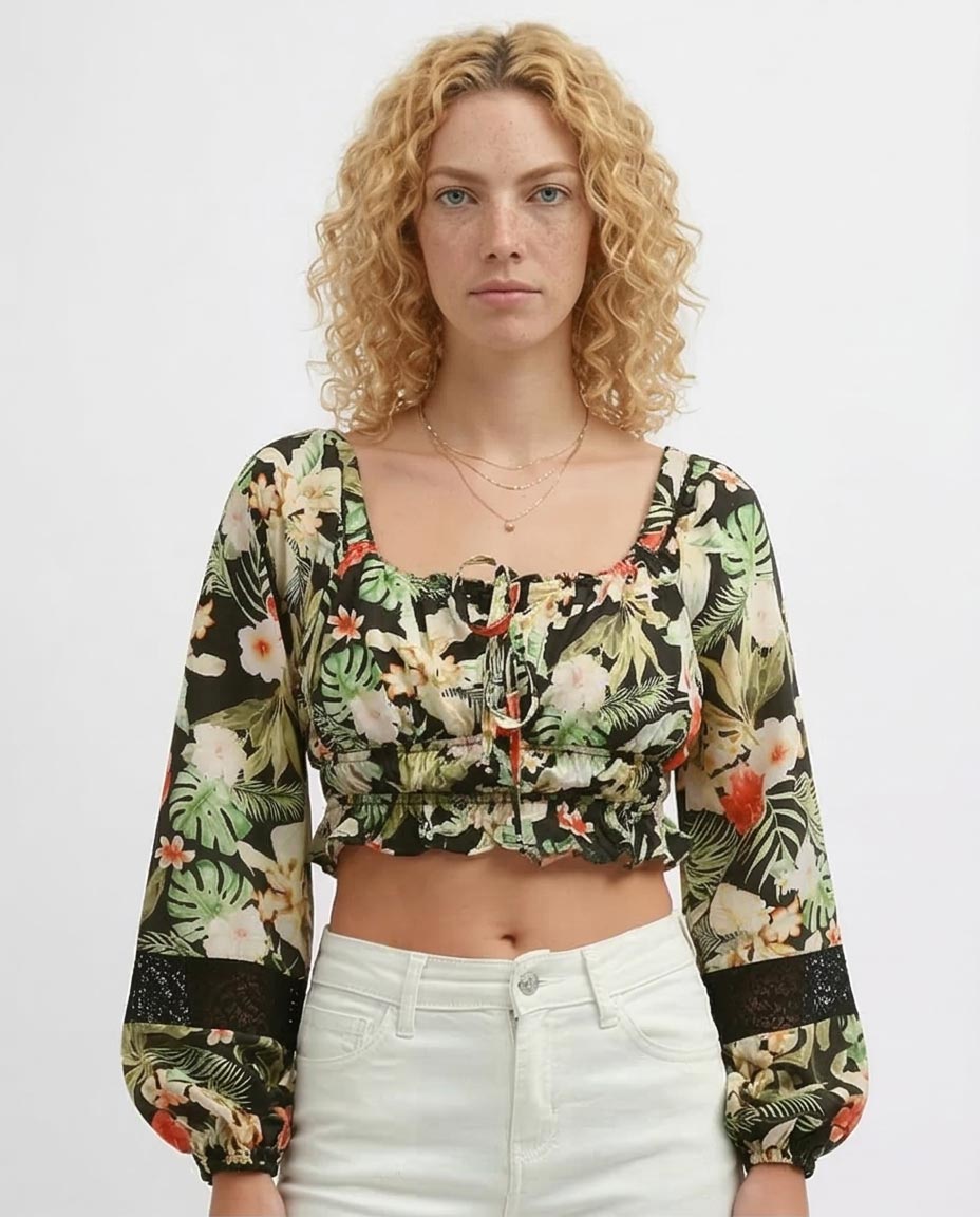 Woman wearing a floral long-sleeve top and white pants on a plain background