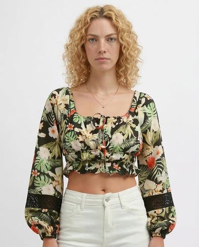 Woman wearing a floral long-sleeve top and white pants on a plain background
