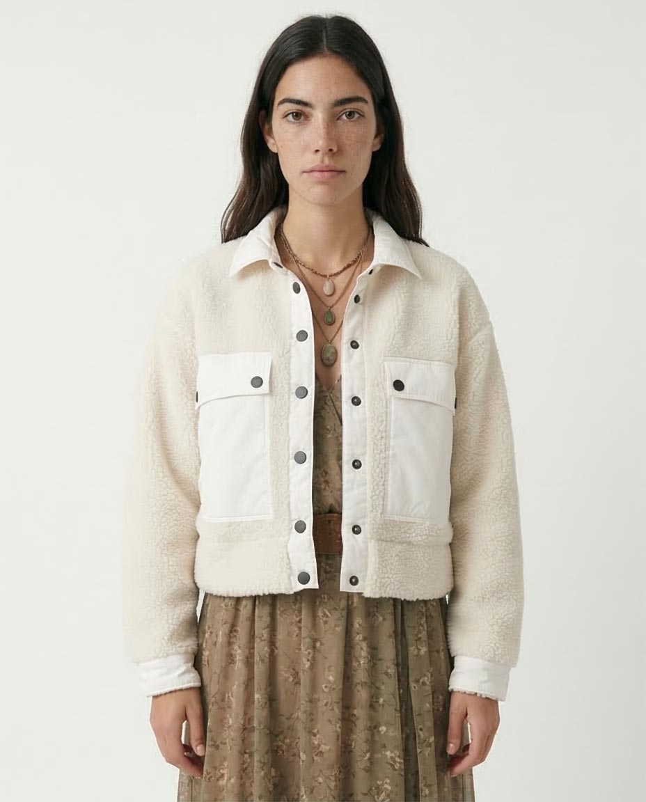 Woman wearing a cream-colored jacket with black buttons on a white background