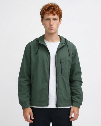 Man wearing a green jacket over a white shirt on a light gray background