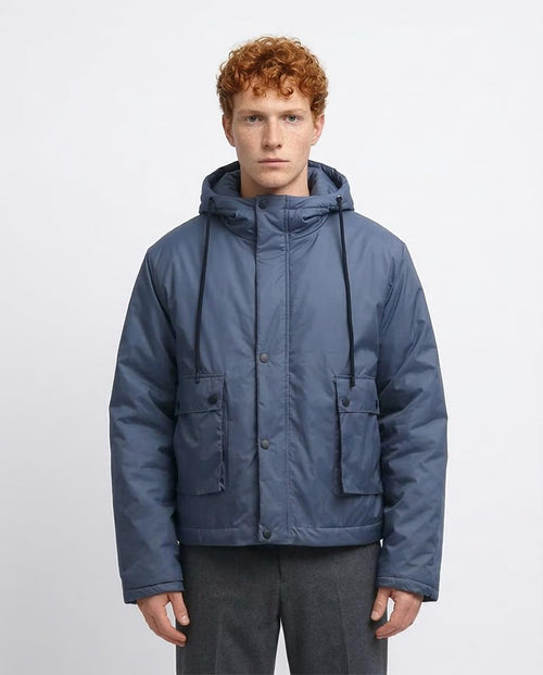 Man wearing a blue hooded jacket on a light gray background