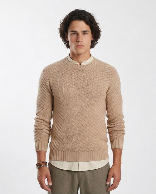 Man wearing a beige knitted sweater over a white shirt on a white background