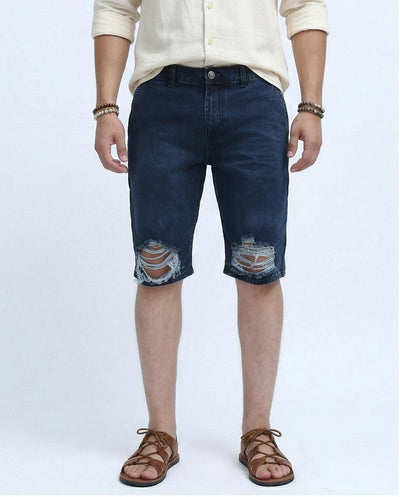 Person wearing blue denim shorts with slight distressing on a white background