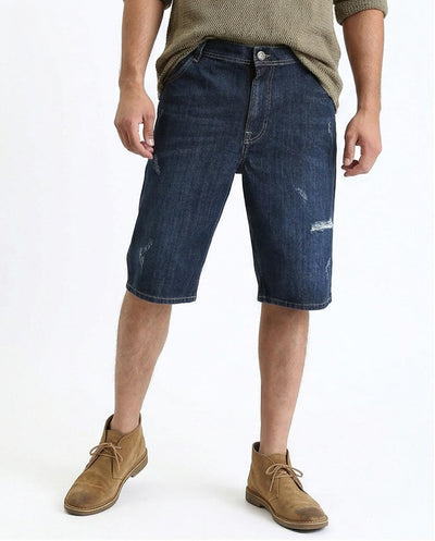 Person wearing dark blue denim shorts and brown shoes on a white background