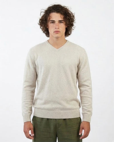 Man wearing a beige sweater and green pants on a white background