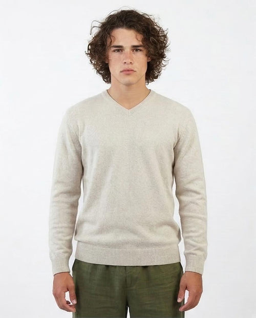 Man wearing a beige sweater and green pants on a white background