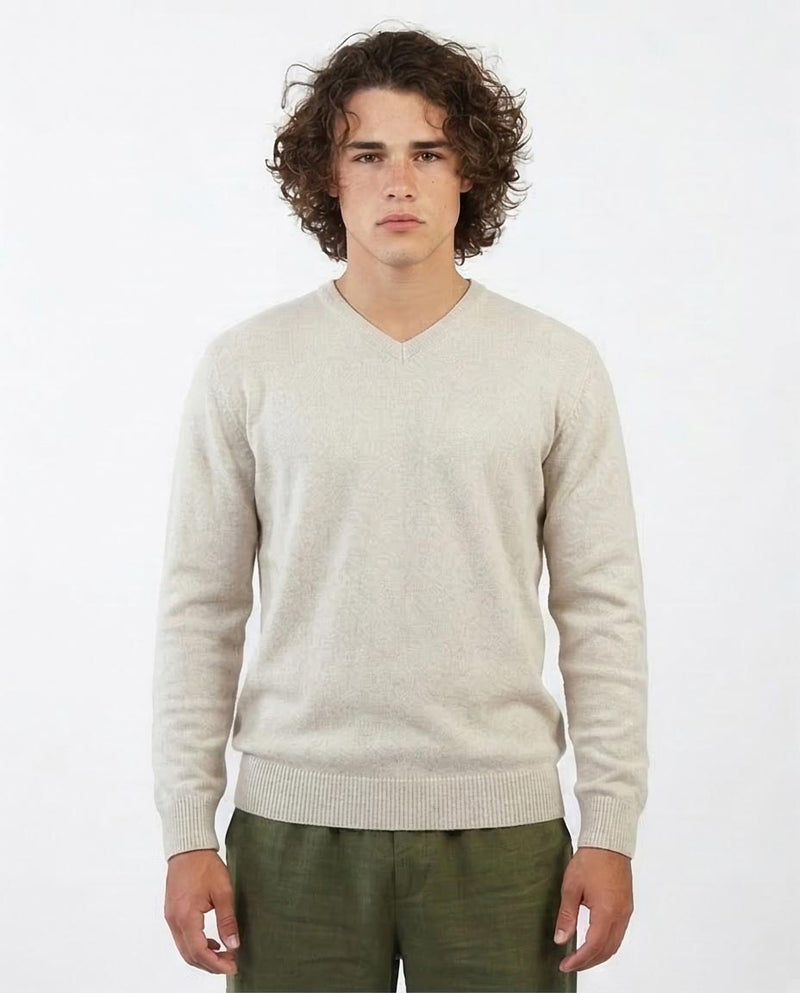 Man wearing a beige sweater and green pants on a white background