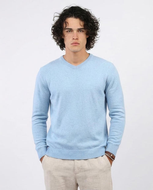 Man wearing a light blue sweater against a white background