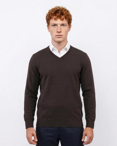 Man wearing a brown sweater over a white shirt on a light gray background