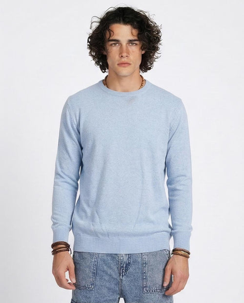 Man wearing a light blue sweater and jeans on a white background