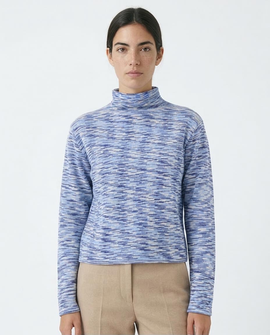 Woman wearing a blue marled turtleneck sweater on a white background