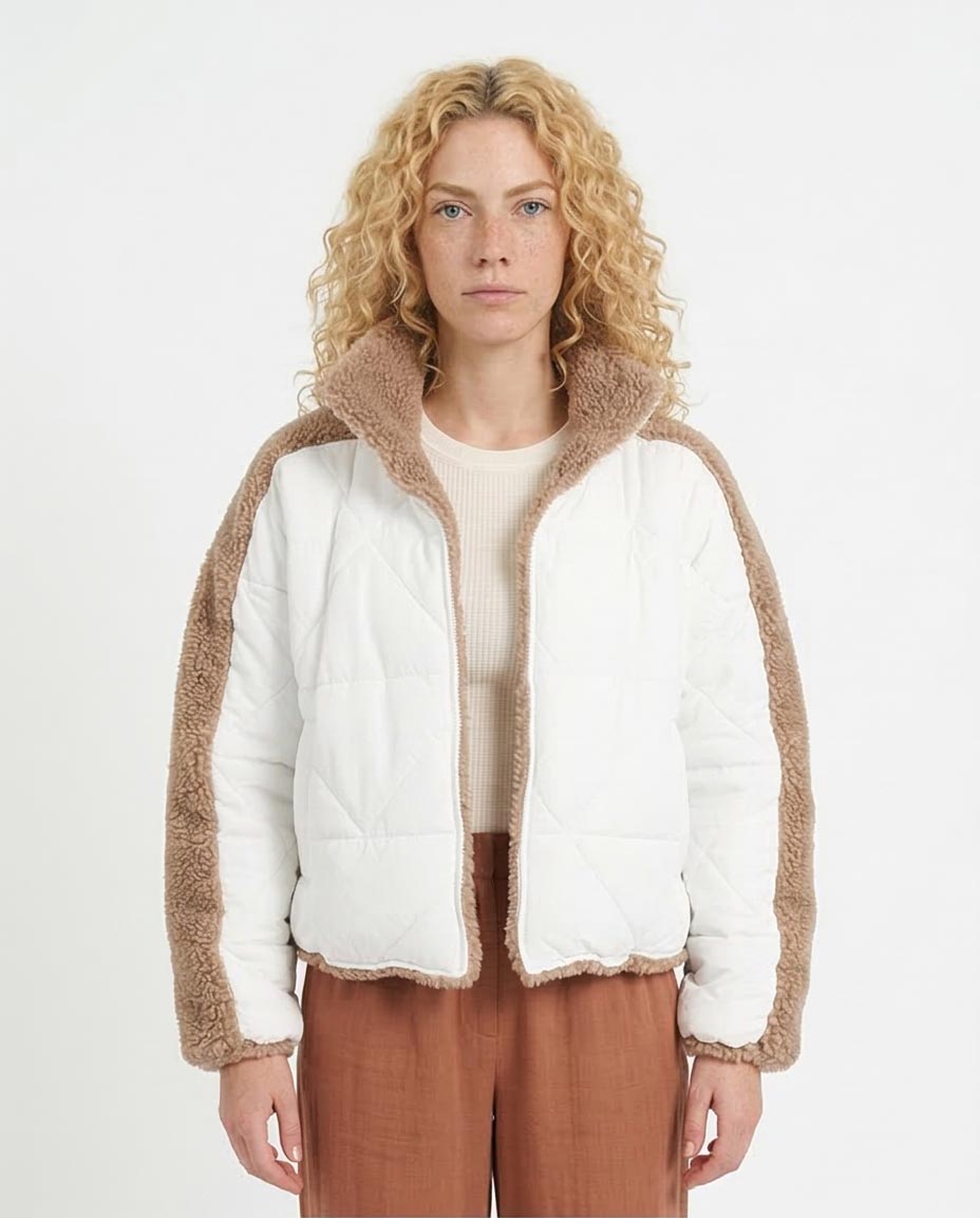 Woman wearing a white puffer jacket with brown trim on a white background