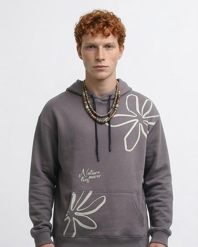Person wearing a gray hoodie with floral designs and text on a light gray background