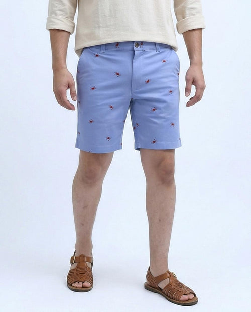 Person wearing light blue shorts with small red patterns on a white background