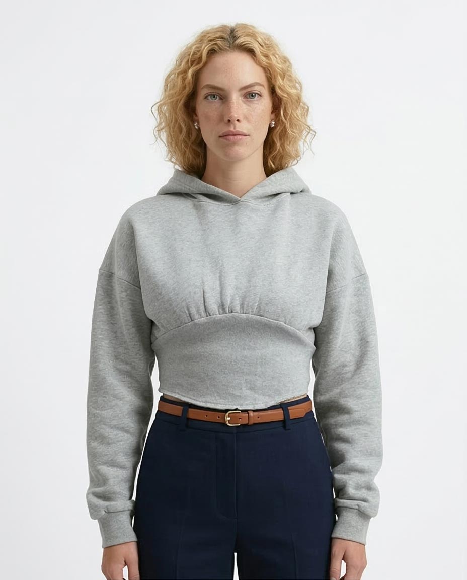 Woman wearing a gray hoodie and navy pants on a light gray background