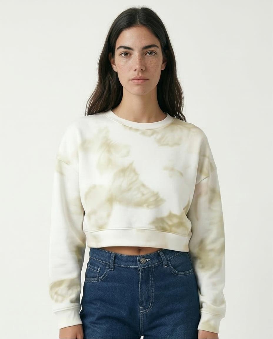 Person wearing a tie-dye sweatshirt and jeans on a plain background