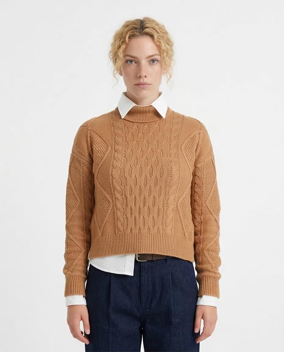 Person wearing a brown cable knit sweater over a white shirt with a plain background